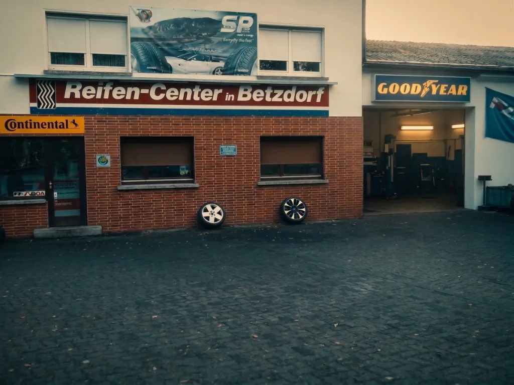 Außenansicht des Reifen Center Betzdorf in der Friedrichstraße 49: Backsteingebäude mit Beschilderung, Hof und offener Werkstatthalle